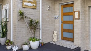 A building with a wooden door, a sign reading "Beach House," and various potted plants.