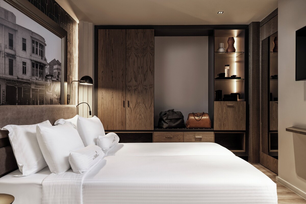 Un dormitorio moderno con una cama grande, armario de madera y vistas a la ciudad.