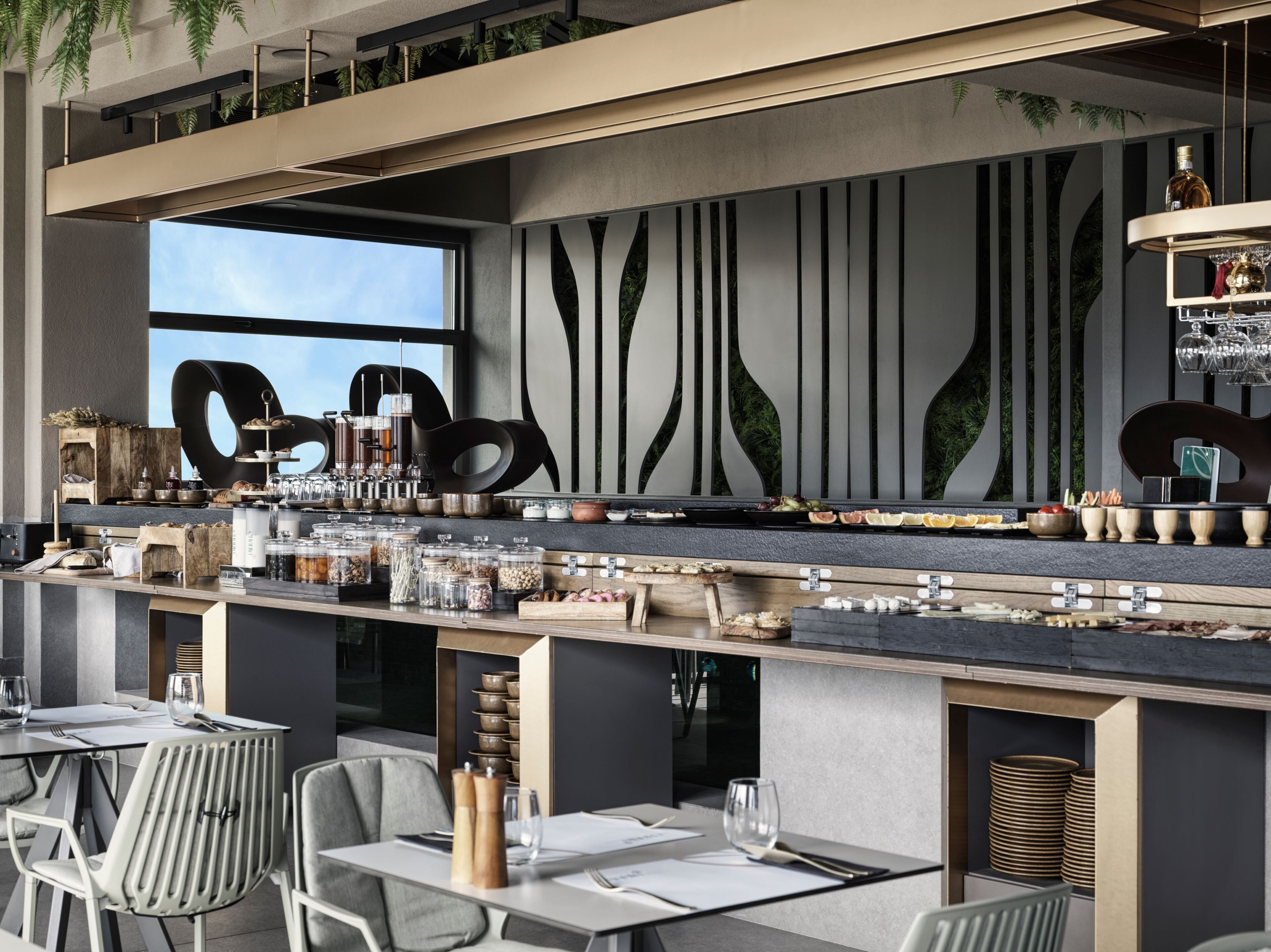 Un bar moderno con una barra larga, distintos vasos y una pared decorativa con líneas verticales.