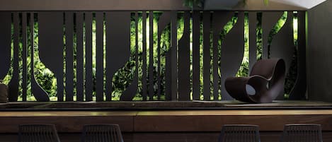 A modern pool area with a seating arrangement of chairs and a decorative wall with vertical slats.