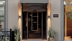 Exterior del hotel Channia, con fachada moderna, entrada destacada y plantas en macetas a la entrada.