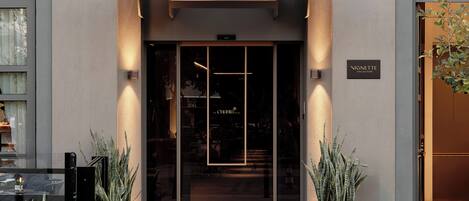 The exterior of the Channia Hotel with a modern facade, a prominent entrance, and potted plants at the entrance.