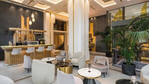 Un vestíbulo moderno con zona de bar, asientos y ventanas amplias.