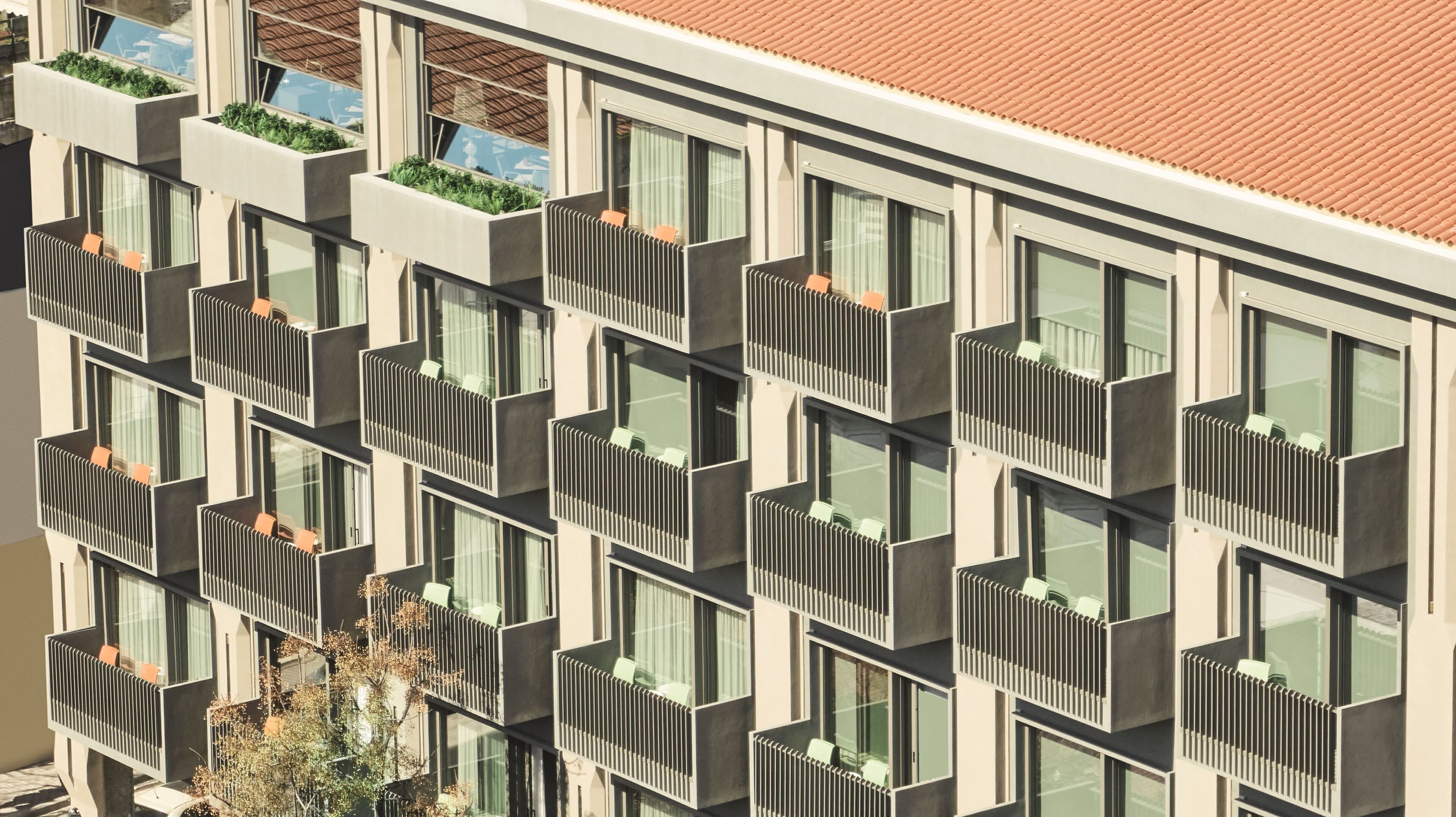 Un edificio moderno con varios balcones, cada uno con un pequeño jardín.