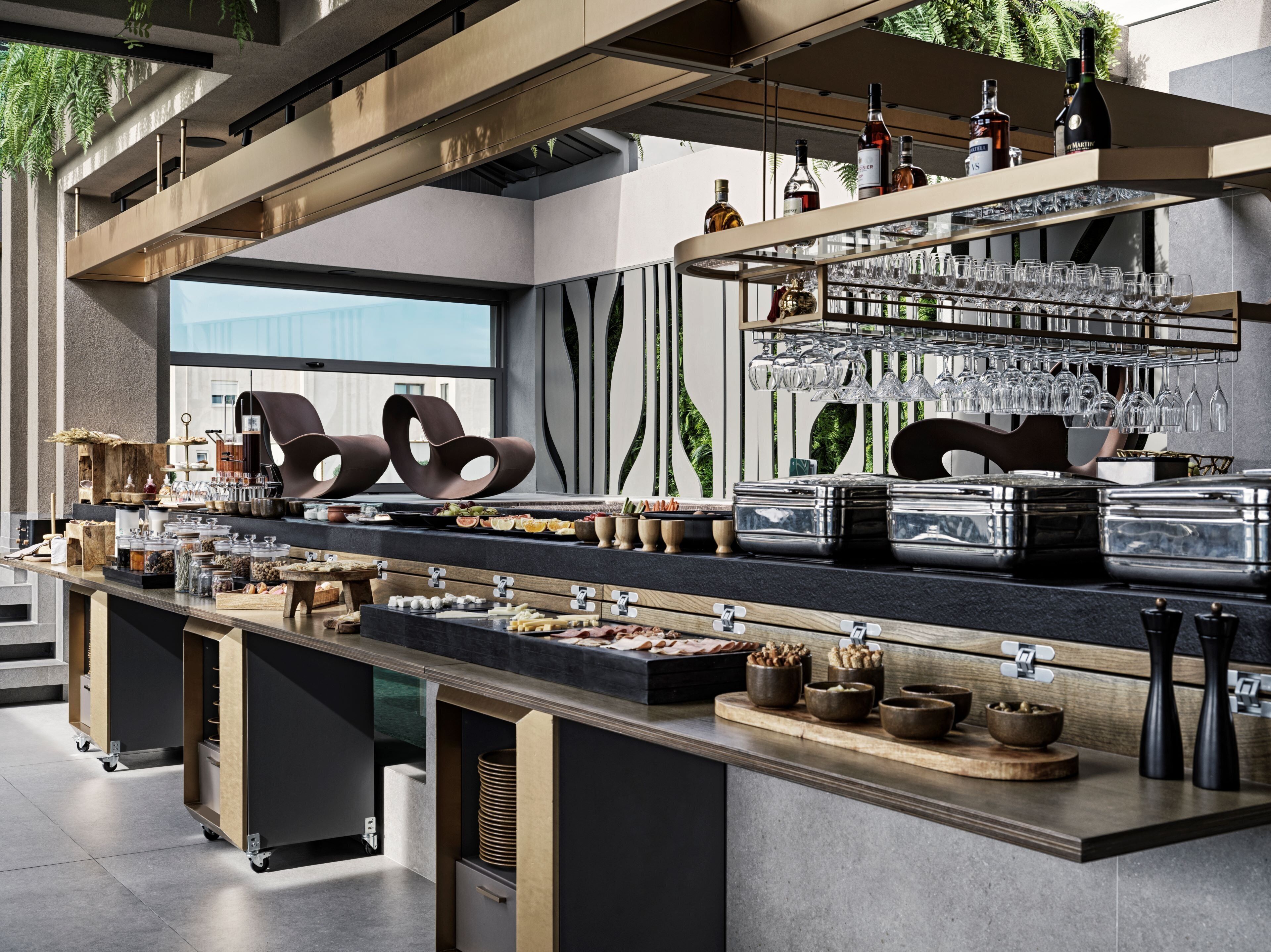 A modern bar area with a variety of glassware, bottles, and food items.