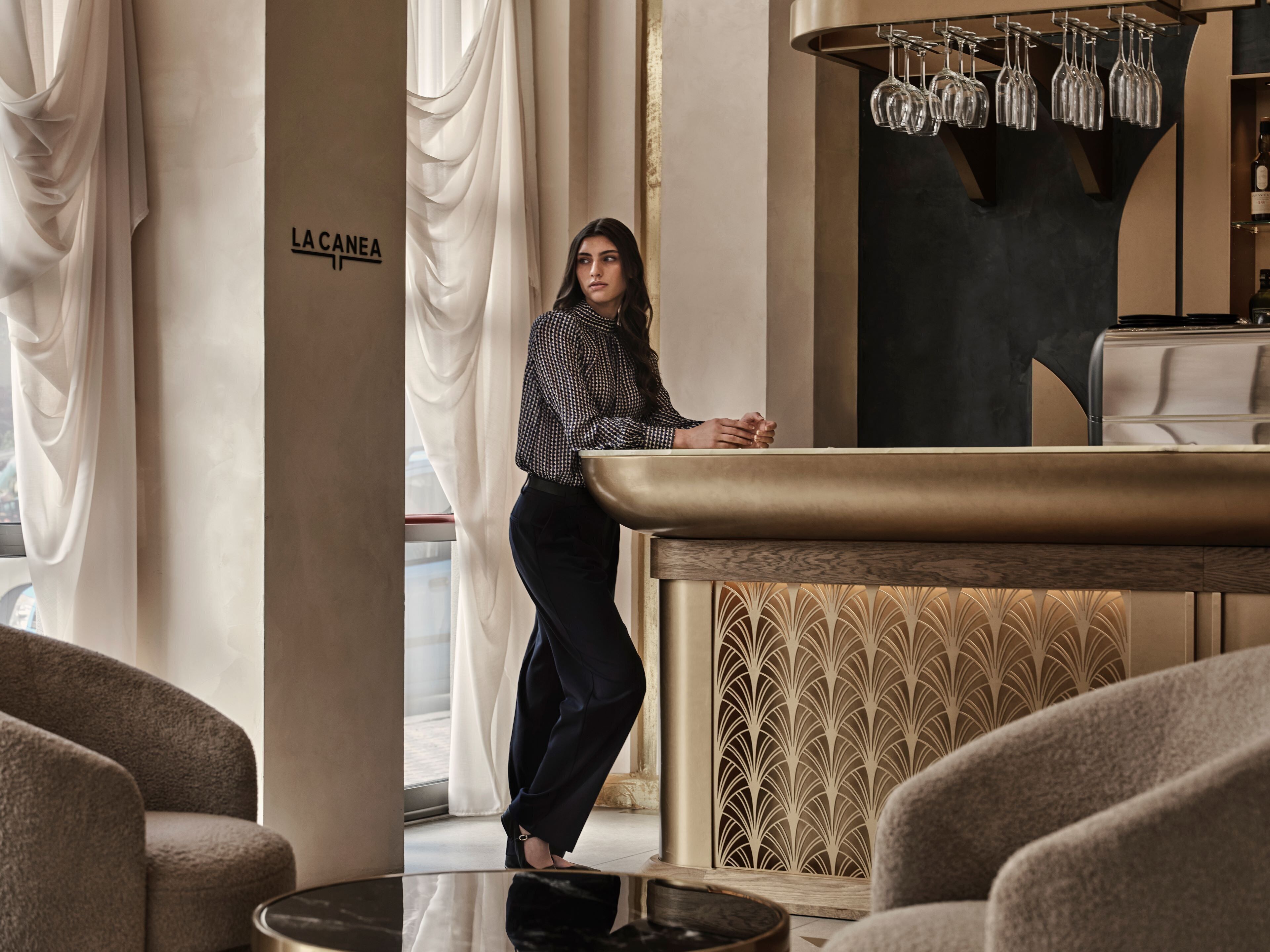 Un interior moderno con una zona de bar, asientos y un letrero que dice "LA CANEA".