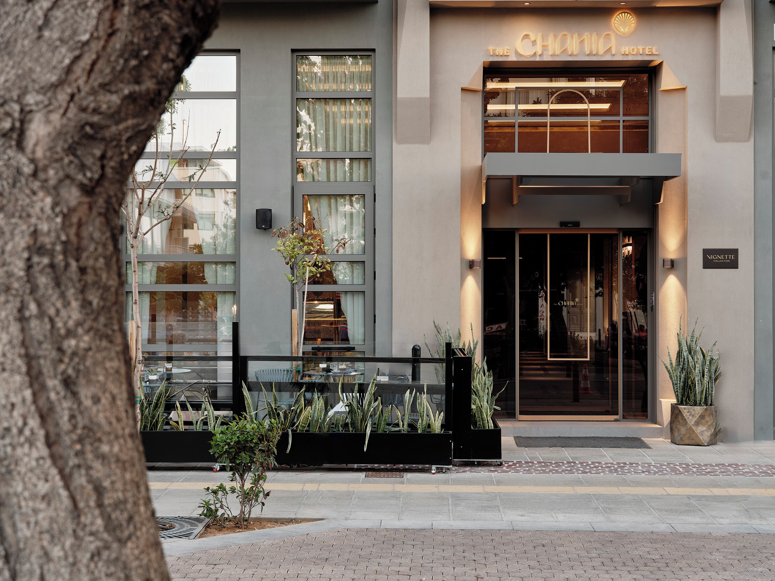 En moderne hotelindgang med en glasfacade, et skilt med 'The Chama Hotel' og et skilt for 'Nignette Collection'.