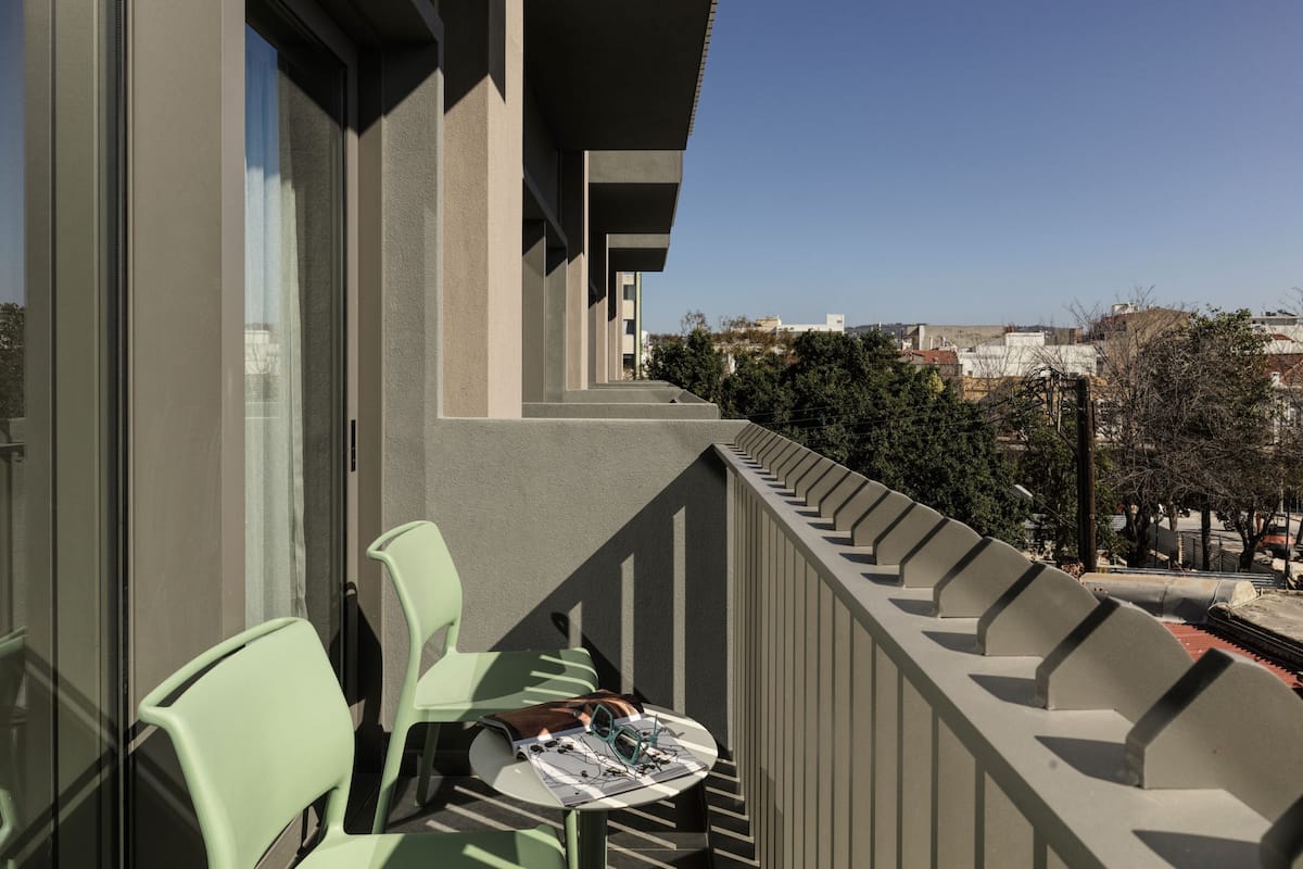 Un balcon avec une table et des chaises, donnant sur un paysage urbain.
