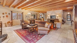 A spacious living room with a high wooden ceiling, leather sofas, a coffee table, and a red patterned rug. - Casa La Vereda | Luxury Retreat Near Plaza (Santa Fe)