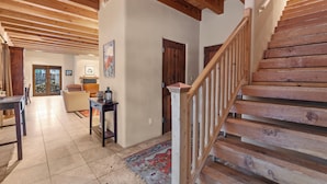 A wooden staircase with a handrail, a patterned rug, and a door leading to another room. - Casa La Vereda | Luxury Retreat Near Plaza (Santa Fe)