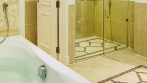 Un baño con bañera, ducha y cabina de ducha con mampara de vidrio.