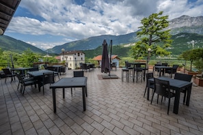 Un patio al aire libre con mesas y sillas, una lámpara y vistas a montañas.