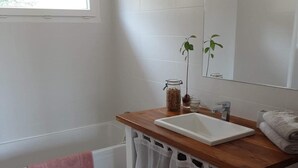 Ein Badezimmer mit Holzbeschlag, einem weißen Waschbecken, einem Spiegel, einem Fenster und einem Handtuchhalter.