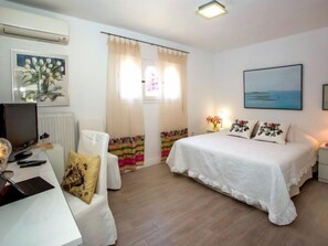 Ein Hotelzimmer mit Bett, Schreibtisch, Computer, Stuhl und Fernseher.
