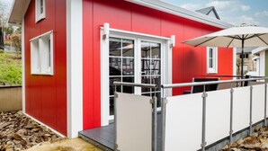 A red and white building with a covered outdoor seating area and a metal railing.