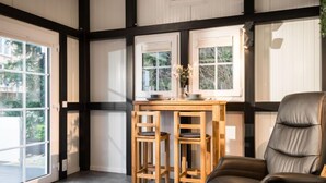 A room with a wooden table and two chairs, a leather sofa, and large windows with blinds.