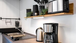 A modern kitchen with a built-in stove, a coffee maker, and a toaster on a wooden countertop. - Tiny Haus Westerwald 16 Green by Interhome (Bad Marienberg)