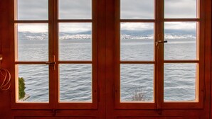 Una porta in legno con quattro finestre, ognuna con vista su una città costiera e montagne sullo sfondo.