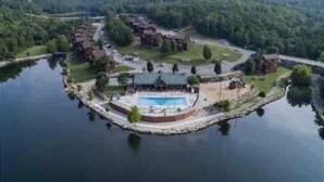 Vista aérea de um resort à beira do lago, com piscina, vários edifícios e vegetação ao redor.