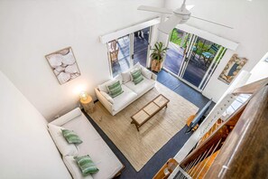 Amplia sala de estar con sofá blanco, una mesa de centro y un gran ventanal con vistas al exterior.