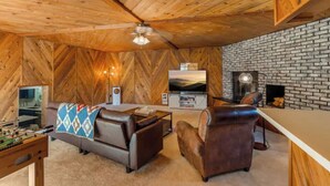 Una sala de estar acogedora con chimenea, paredes de madera, televisor y muebles de cuero.