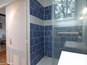 Bathroom features a glass shower enclosure, white sink, and wooden floor.