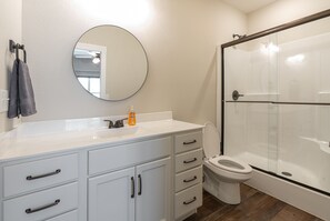 Bathroom features a white vanity, toilet, and glass-enclosed shower area.