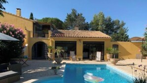 A pool area with a clear blue pool, a lounge chair, and a small inflatable boat. - Maison Méridional au Coeur D'uzès (Uzès)