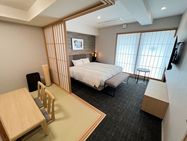 Una habitación de hotel moderna con cama, escritorio, silla, mesita y televisor.