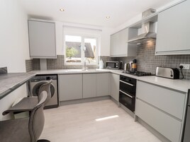 A modern kitchen with a built-in washing machine, a microwave, a toaster, and a stove.