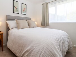 A neatly made bed with a grey headboard, two pillows, and a white bedspread. There are two framed artworks on the wall above the bed.