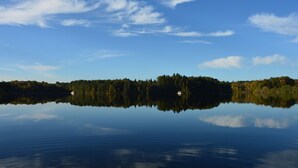 Un lago tranquilo con una isla boscosa y una pequeña cabaña.