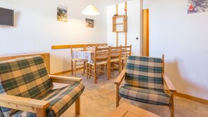 A cozy room with two plaid sofas, a wooden dining table with chairs, a hanging light fixture, and a painting on the wall.