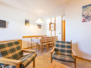 Um quarto acolhedor com dois sofás xadrez, uma mesa de jantar de madeira com cadeiras, um lustre e um quadro na parede.