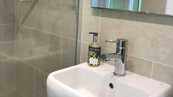 Ein Badezimmer mit einem weißen Waschbecken, einer Handbrause und einer Seife.