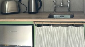 Keittiössä on pesuallas, vedenkeitin, leivänpaahdin ja hyllyjä, joilla on keittiötarvikkeita.