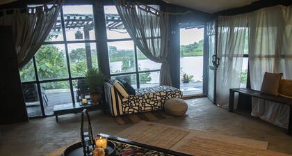 CABIN LOCATED ON A HILL NEXT TO THE FOREST WITH A VIEW OF THE LAKE