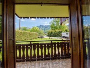 A balcony with a view of a green landscape, a white van, and a mountain in the background.