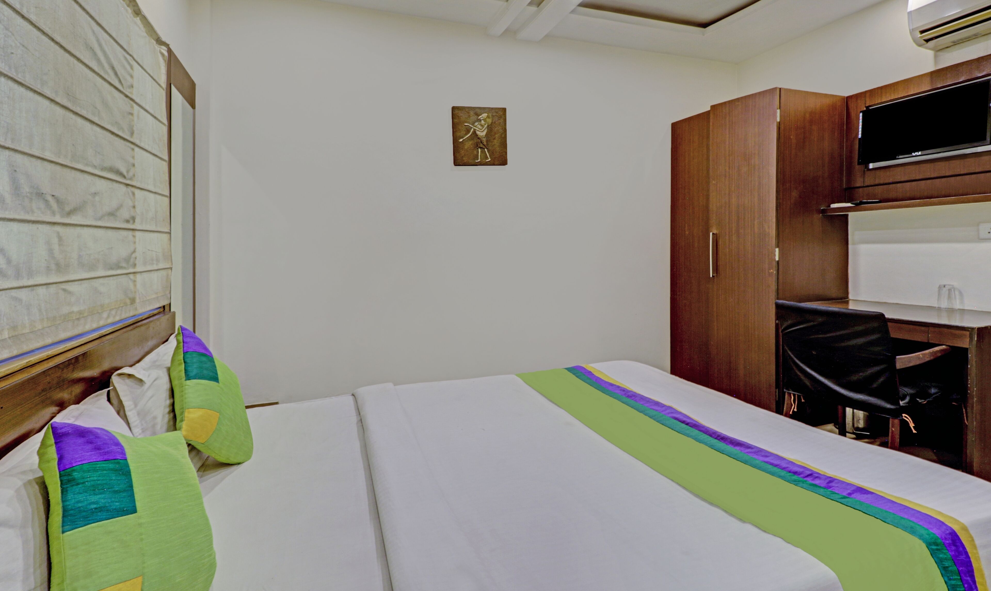 Una habitación de hotel con una cama, un escritorio, una silla y un equipo de aire acondicionado.