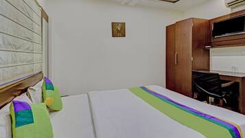 Una habitación de hotel con una cama, un escritorio, una silla y un equipo de aire acondicionado.