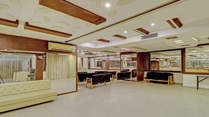 A spacious hotel lobby with a white sofa, multiple seating areas, and a large mirror reflecting the interior. -  Loharkar Hotel (Nagpur)