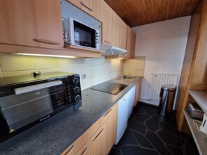 A compact kitchen with a built-in oven, microwave, and a small sink. - Bright 3-room apartment, sleeps 8, near slopes (La Plagne)