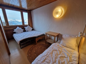 Un dormitorio con dos camas, una mesita y una lámpara en la pared.