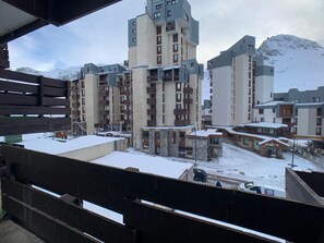 Un área residencial cubierta de nieve con edificios de varios pisos, incluyendo un hotel destacado con balcones y un centro de esquí al fondo.