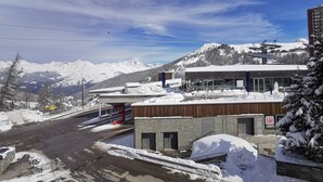 Un albergo con una seggiovia sullo sfondo, circondato da montagne innevate.