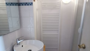 A bathroom with a white sink, a mirror, and a shower area.