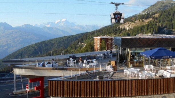 Un ristorante con posti a sedere all'aperto e vista su un paesaggio montuoso.