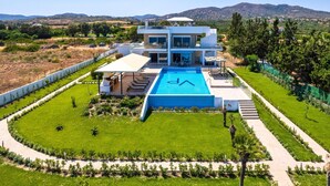 A modern villa with a swimming pool, a covered outdoor area, and a view of the surrounding landscape.