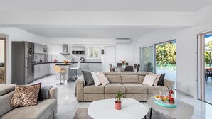 A modern living room with a sofa, coffee table, and a dining area with a table and chairs.