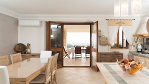 Una cucina moderna con zona pranzo, vista all'esterno e una ciotola di frutta sul bancone.